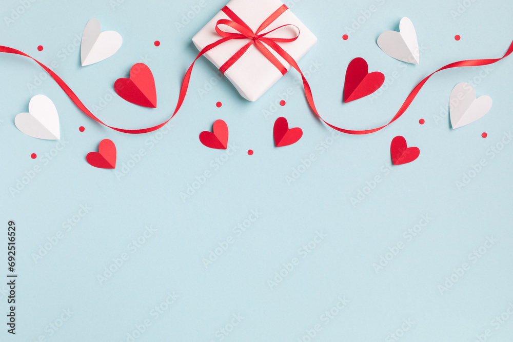 Valentine or mother day festive composition with gift or present box and red hearts on pastel blue background top view. Flat lay style. - obrazy, fototapety, plakaty 