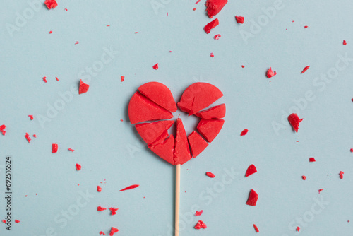 Valentine day concept with broken red lollipop heart on pastel blue background top view. Flat lay greeting card.. photo