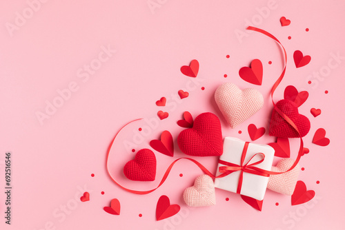 Valentine or mother day festive composition with gift or present box and red hearts on pastel pink background top view. Flat lay greeting card.