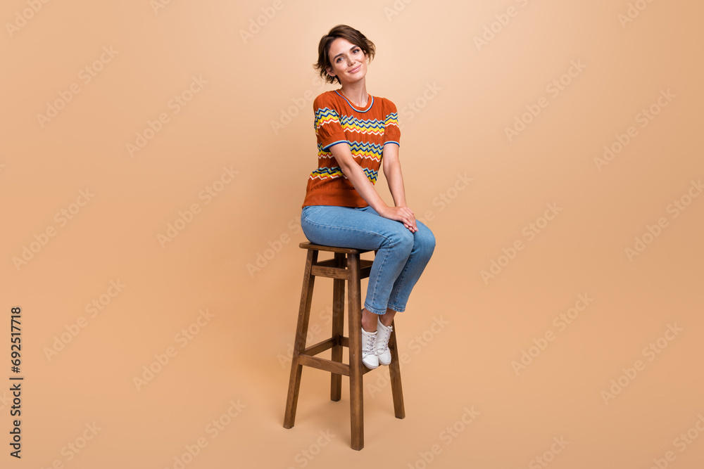 Fototapeta premium Full size photo of lovely satisfied peaceful girl sitting chair good mood isolated on beige color background