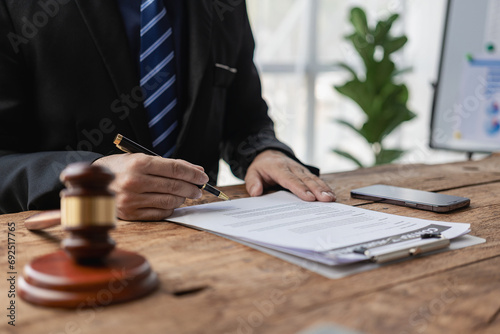 Close up of a businessman lawyer working with a hammer and a judge's scale for a lawyer consulting concept on documents. Law, advice and justice concept