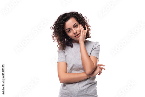 authentic cute slim curly woman with black hair dressed in casual gray t-shirt on white background with copy space