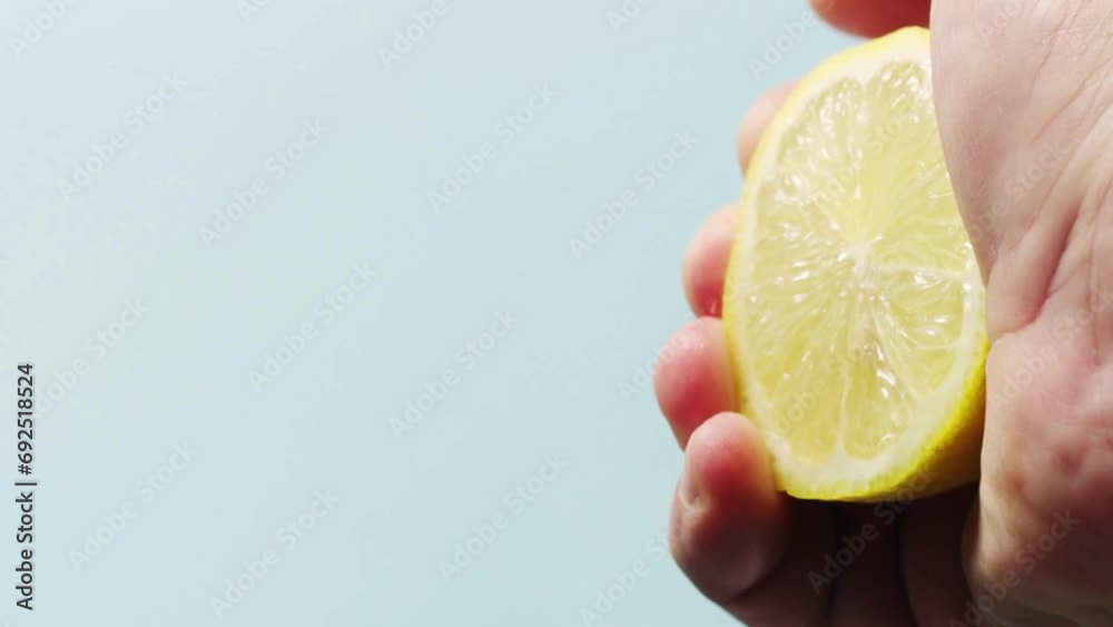Closeup shot of person's hands squeezing lemon juice. Human squeezes half of lemon.