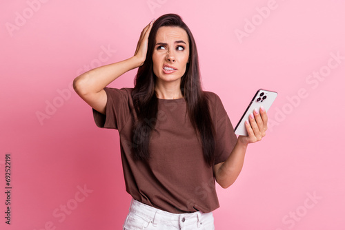 Portrait of young unsatisfied lady grin teeth using smartphone touch head look empty space oops failed isolated on pink color background
