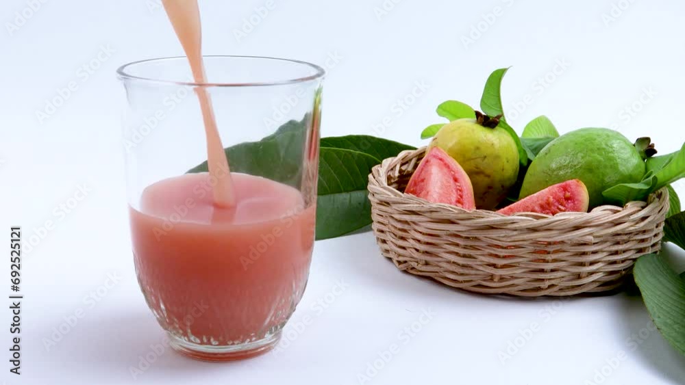 Guava juice and fresh red guava in a woven bamboo basket with green leaves on a white background Guava juice and fresh red guava in a woven bamboo basket with green leaves on a white background