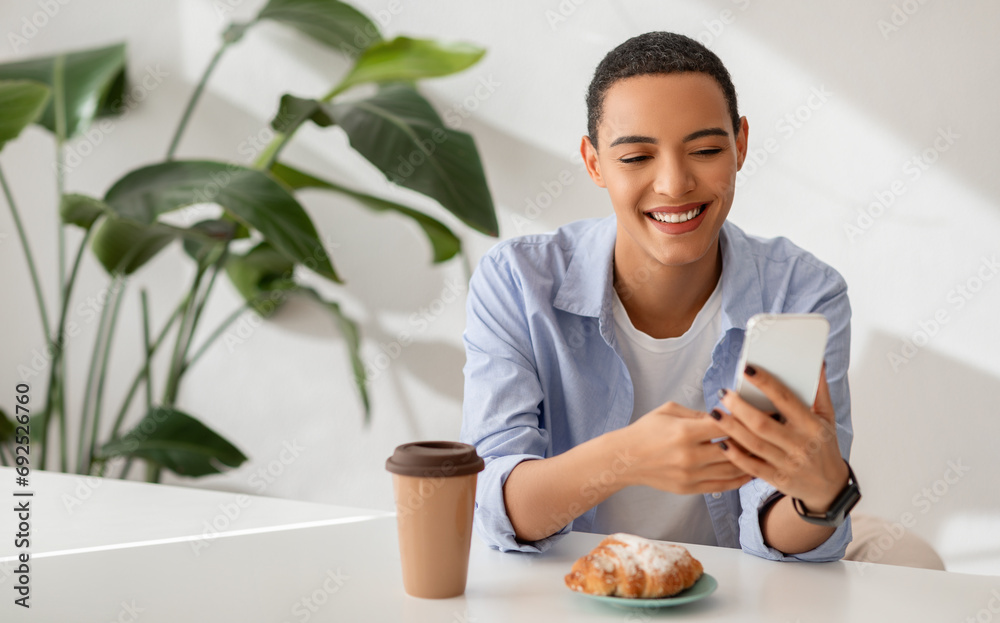Happy young woman in casual enjoys coffee break, texting on her smartphone Happy young woman in casual enjoys coffee break, texting on her smartphone