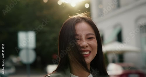 Portrait of stylish asian woman wearing trench coat posing in the street, happy. photo