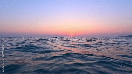 View from the surface of the sea at sunset. Chilling on the sea waves and watching the setting sun go below the horizon photo