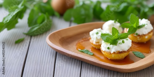 Goat Cheese Poppers: honey drizzle, mint leaves on the wooden table minimalist with bokeh lights background