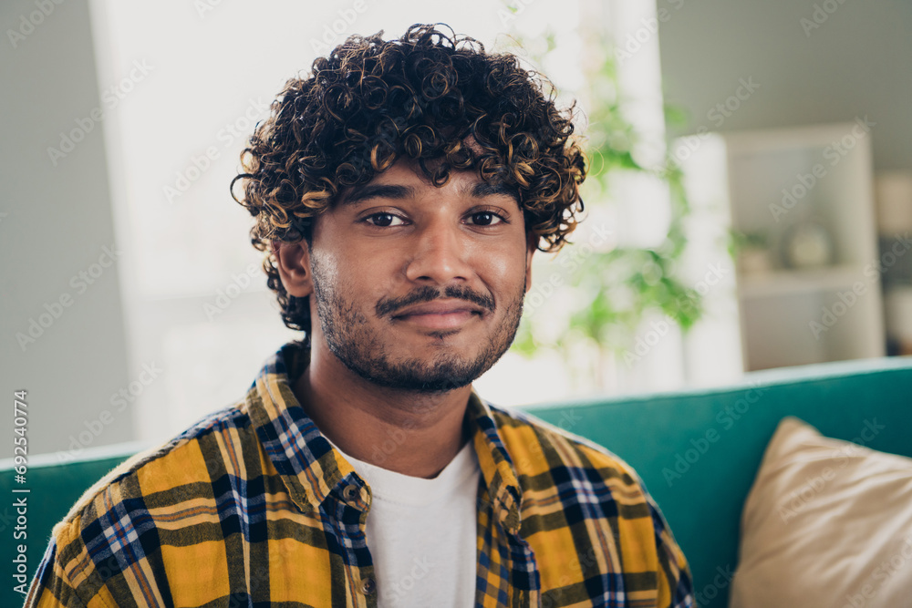 Portrait of satisfied peaceful young man sit sofa good mood pastime chilling living room house indoors