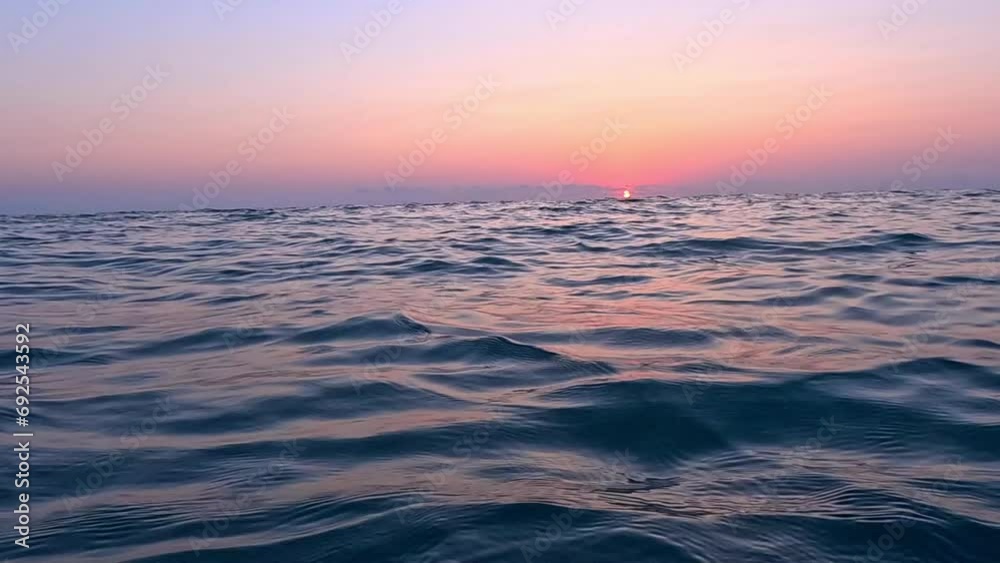 View from the surface of the sea at sunset. Chilling on the sea waves and watching the setting sun go below the horizon View from the surface of the sea at sunset. Chilling on the sea waves and watching the setting sun go below the horizon