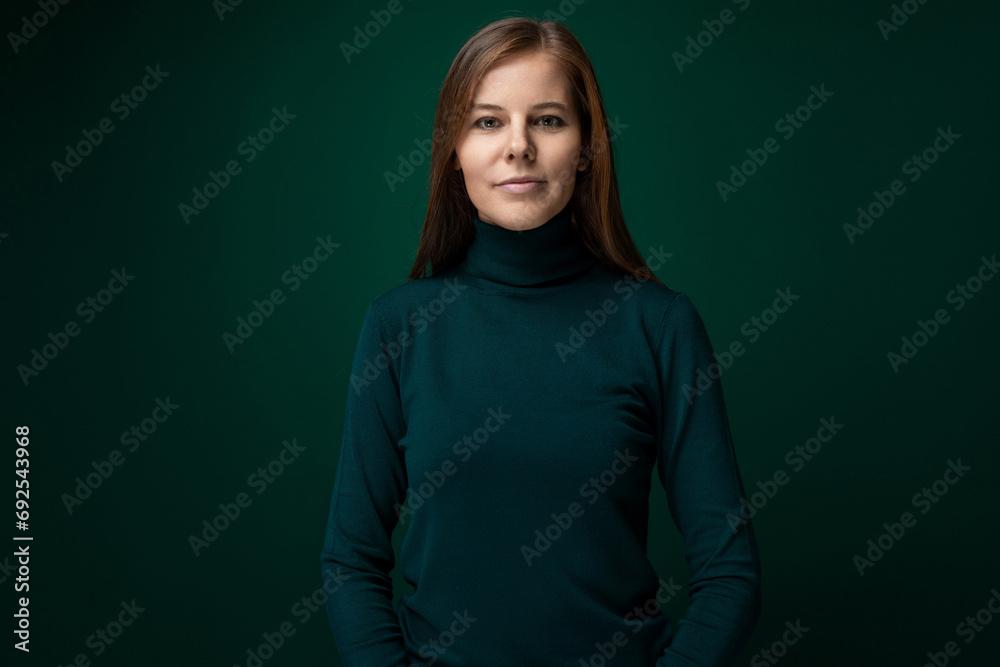 Fototapeta premium Portrait of a well-groomed young woman with brown eyes on a dark green background