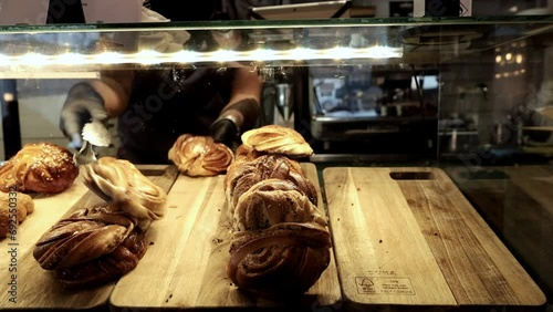 Stockholm, Sweden A server in a cafe fills a display case with sweet buns like cinnamon rolls and croissants.  photo