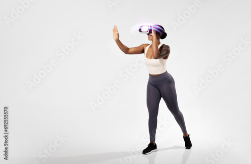 black woman working out wearing virtual reality headset, white studio