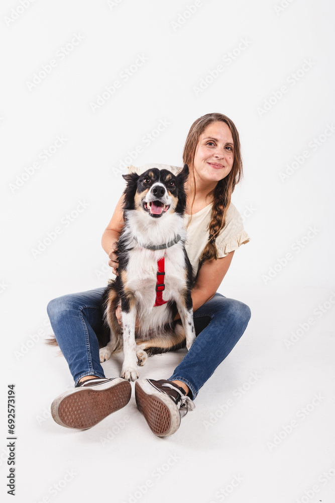 Smiling middle-aged woman posing with her dog in a studio shot on white background