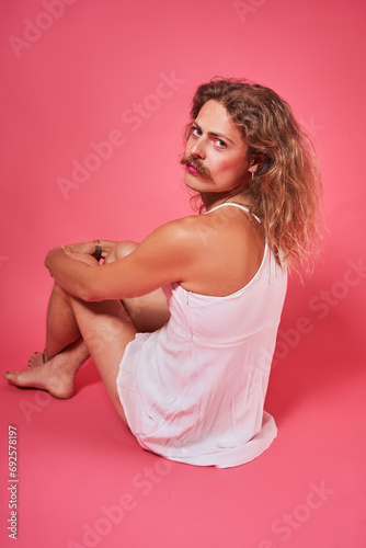 Serious longhaired man with moustaches looking of his shoulder while posing