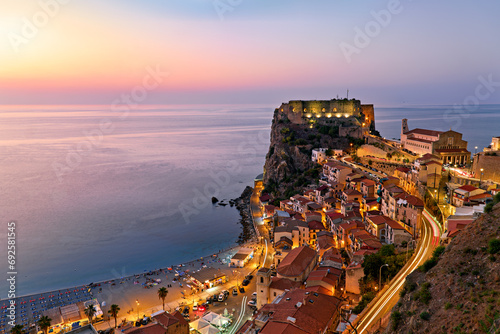 The city of Scilla Calabria Italy. Elevated view of the illuminated Ruffo castle at sunset photo