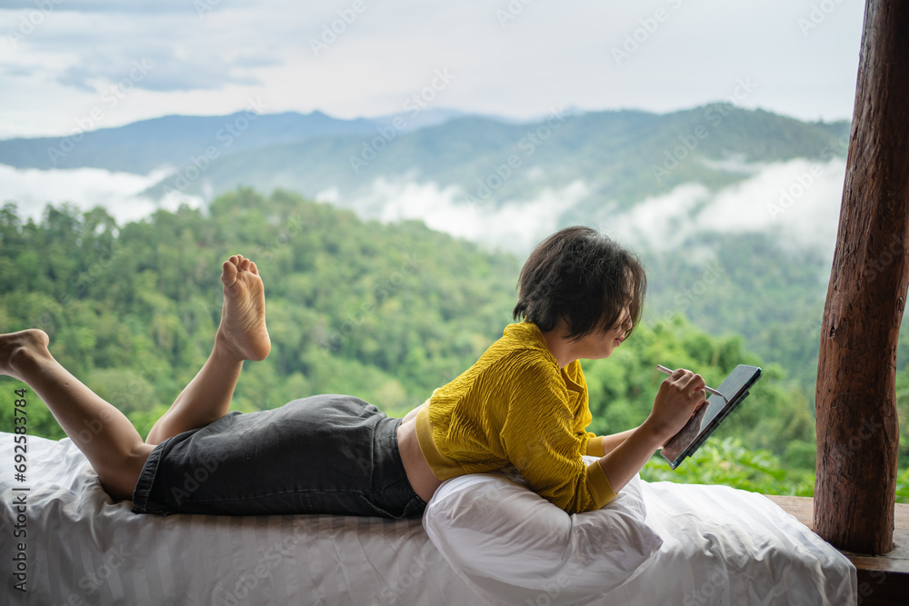 Asian woman freelancer traveler working online using tablet. thinking creative idea in morning of nature cliff mountain.