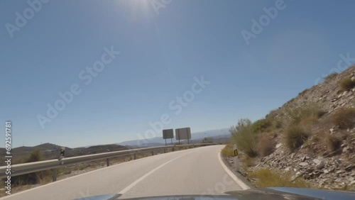 First person view, FPV, from dashcam of car driving mountain road from Calar Alto Observatory to Tabernas Desert in Almeria, Andalusia, Spain, Europe. Road trip in POV, with bright, sunny, clear sky photo