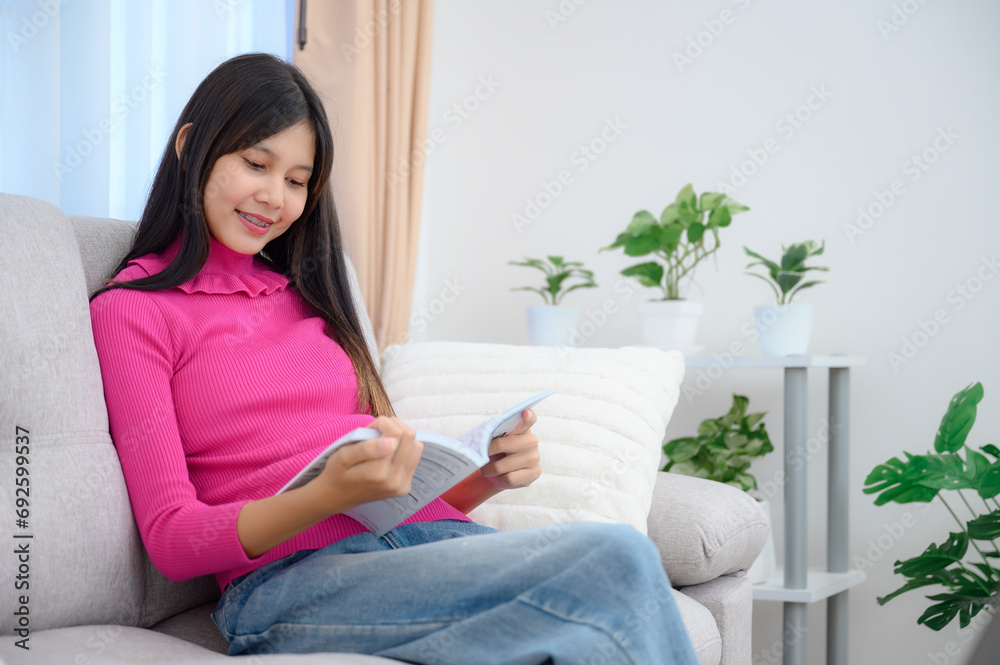 Asian teenage girl Reading a book at her home on the cloth sofa in the living room with a nice holiday at home. Asian teenage girl Reading a book at her home on the cloth sofa in the living room with a nice holiday at home.
