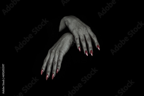 Hanging limply bony pale female hands of vampire with sharp red nails, isolated on black.