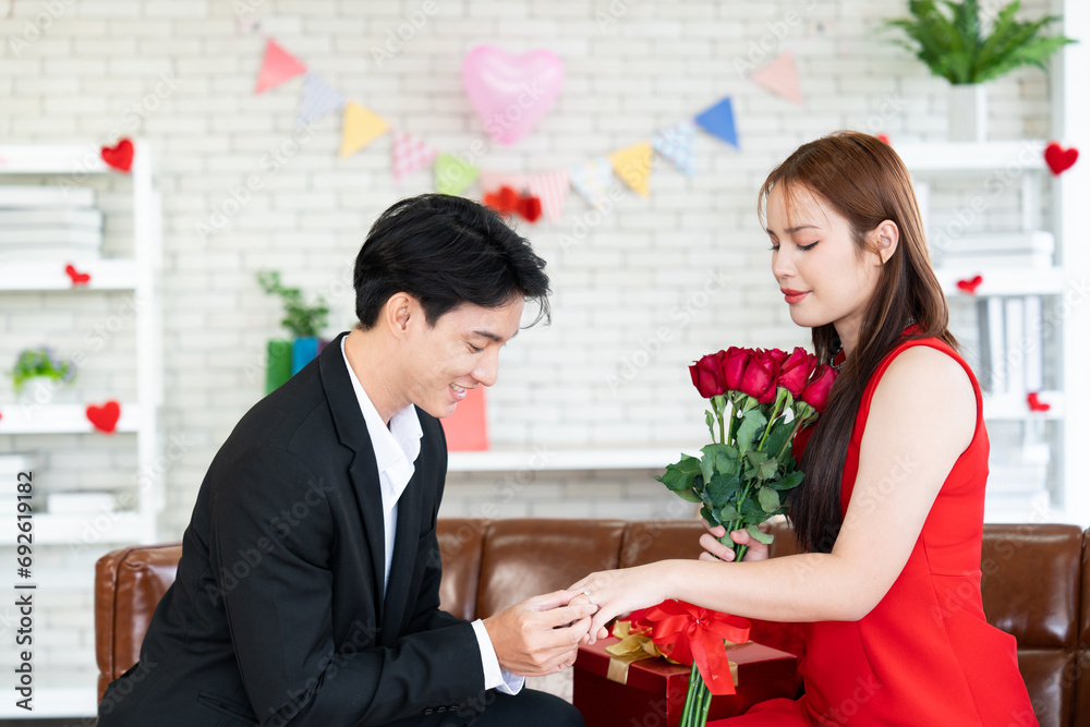 Proposal of marriage with engagement diamond ring and give red rose flower bouquet while Asian couple lover commitment for living together forever in Valentine's Day Proposal of marriage with engagement diamond ring and give red rose flower bouquet while Asian couple lover commitment for living together forever in Valentine's Day