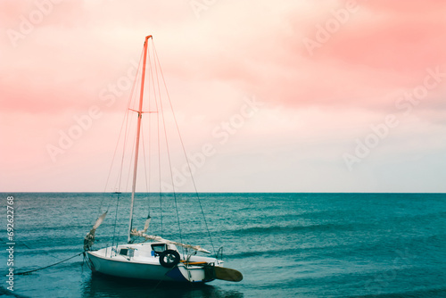 Small sailing boat on the sea, on a background of red sky, surreal seascape photo