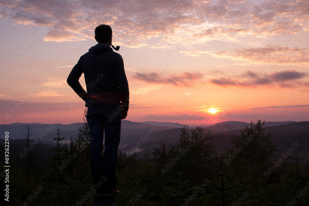 The guy with the Smoking pipe looking at mountainous landscape at sunset