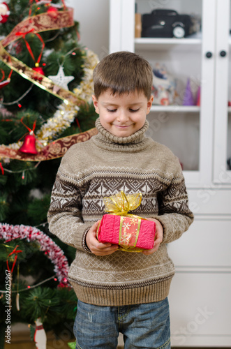 Cute boy in brown sweater holding gift in two hands