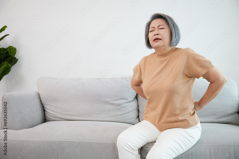 Obraz premium senior woman suffering from back pain on sofa