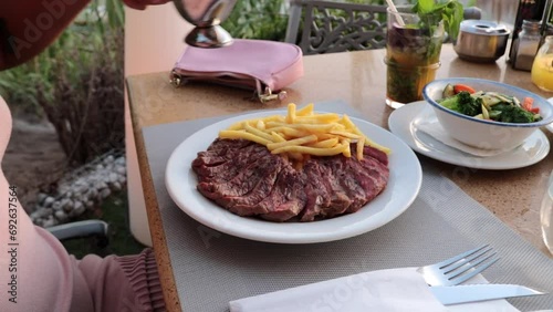 mujer hecha salsa verde sobre un plato con carne y patatas