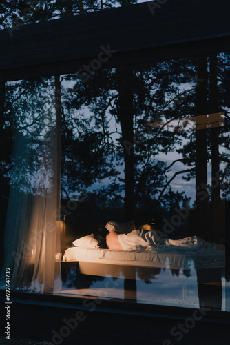 Bedroom in apartment or house with reflection in window glass of night forest.