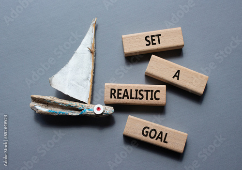Set a realistic goal symbol. Concept words Set a realistic goal on wooden blocks. Beautiful grey background with boat. Business and Set a realistic goal concept. Copy space. photo