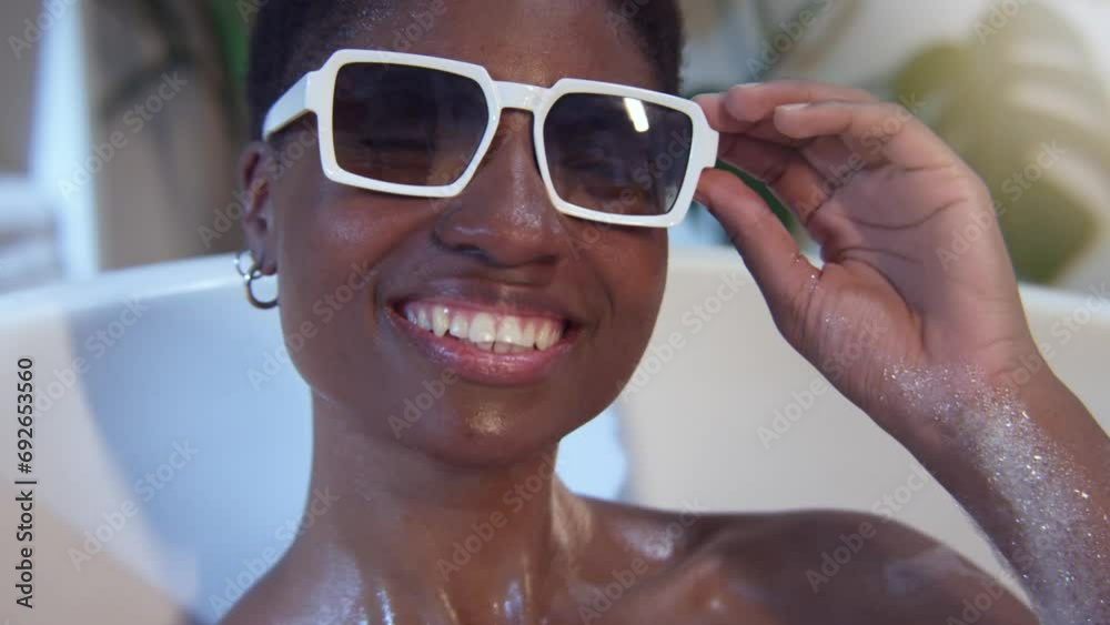 Portrait of an attractive black woman smiling in bathtub with sunglasses looking at camera. High quality 4k footage. Portrait of an attractive black woman smiling in bathtub with sunglasses looking at camera. High quality 4k footage.