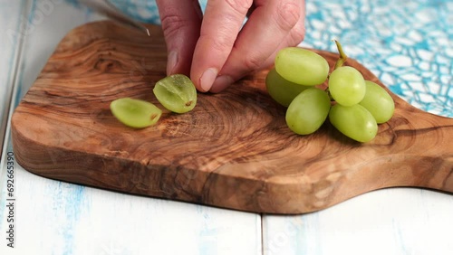 Green grapes without seeds are cut into quarts on a wooden board made of olive wood.