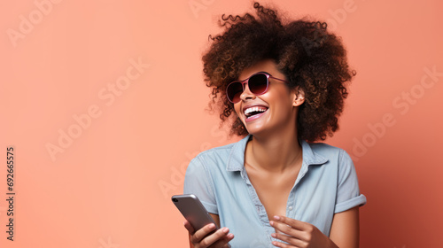 Young girl smiling holding a smartphone sitting against colored background photo