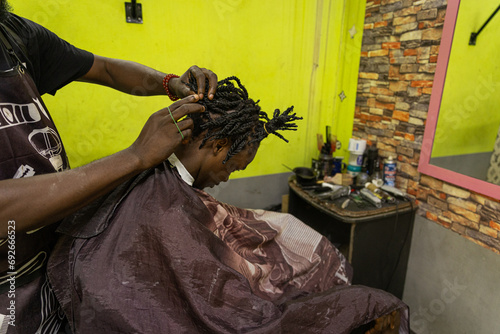A barber fixes his client's braids inside his barbershop
