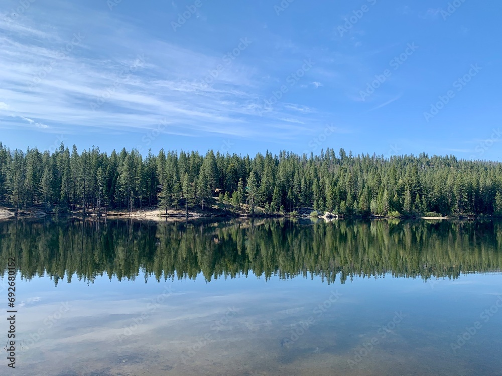a small lake with some trees in the background and sky