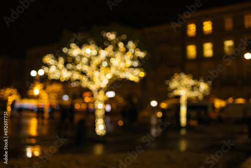 Bokeh night light joyful abstract blur of Christmas festive time background. Blurred christmas market in evening at town hall square in Krakow, Poland.