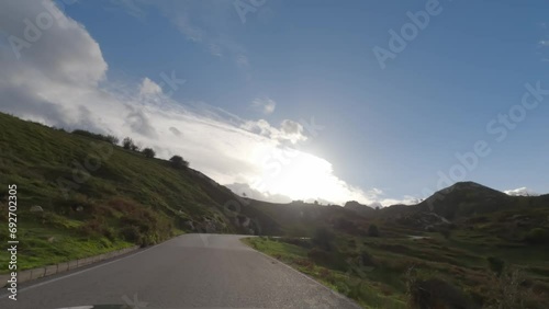 First person view, FPV, from dashcam of car driving winding, high, narrow mountain road to the Covadonga Lakes in Cantabria, Northern Spain, Europe. Road trip video in POV, with clouds and blue sky photo