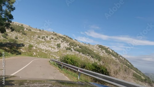 First person view, FPV, from dashcam of car driving mountain road down from Pena Cabarga outside Santander in Cantabria, Northern Spain, Europe. Road trip video in POV, with sunny bright blue sky photo