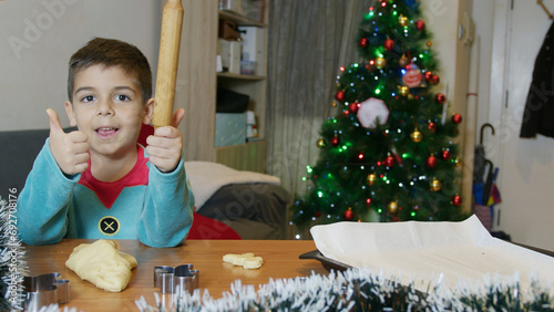 Thumb up. Christmas cookies making. Cute boy dressed as an elf approving gingerbread man cookies baking time. High quality photo photo