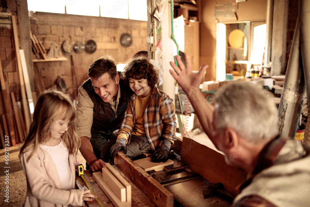 Cute little children working with older carpenters in workshop