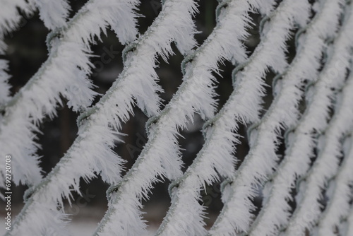 Zimowe rzeźby wiatru na siatce ogrodzeniowej.