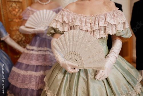 Canvas Print Closeup of ladies wearing big ballgowns holding fans while waiting for partners