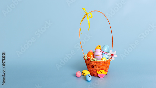 Sticker Easter wicker basket filled with decorative multi colored eggs on a light blue b