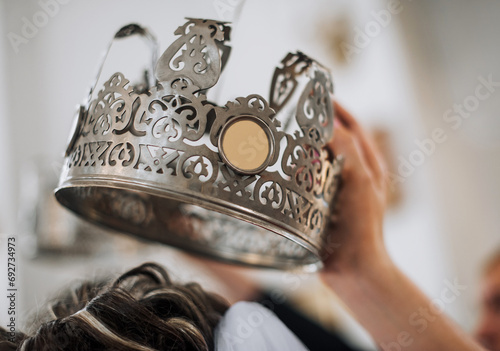 The priest holds a silver crown over the head of the bride in the temple, conducting the wedding ceremony. Close-up photography, religion concept. photo