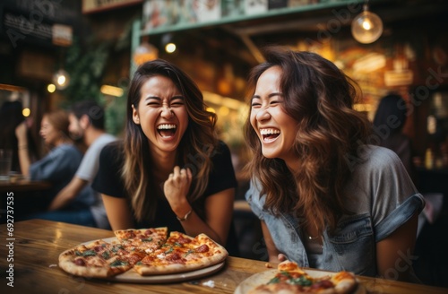 two women laughing with pizza at a restaurant