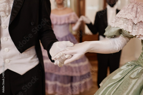 Close up of unrecognizable lady and gentleman holding hands wearing gloves entering ballroom together, copy space photo