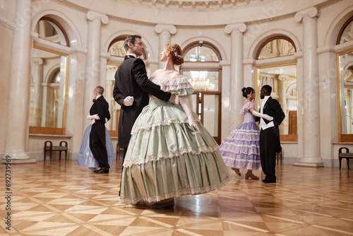 Full length view at couples dancing in palace ballroom and swirling on parquet floor photo